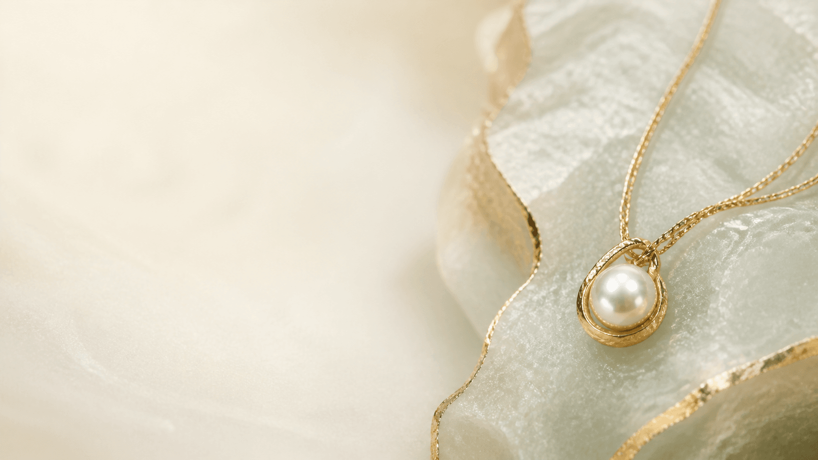 Pearl and gold pendant resting on pale jade stone